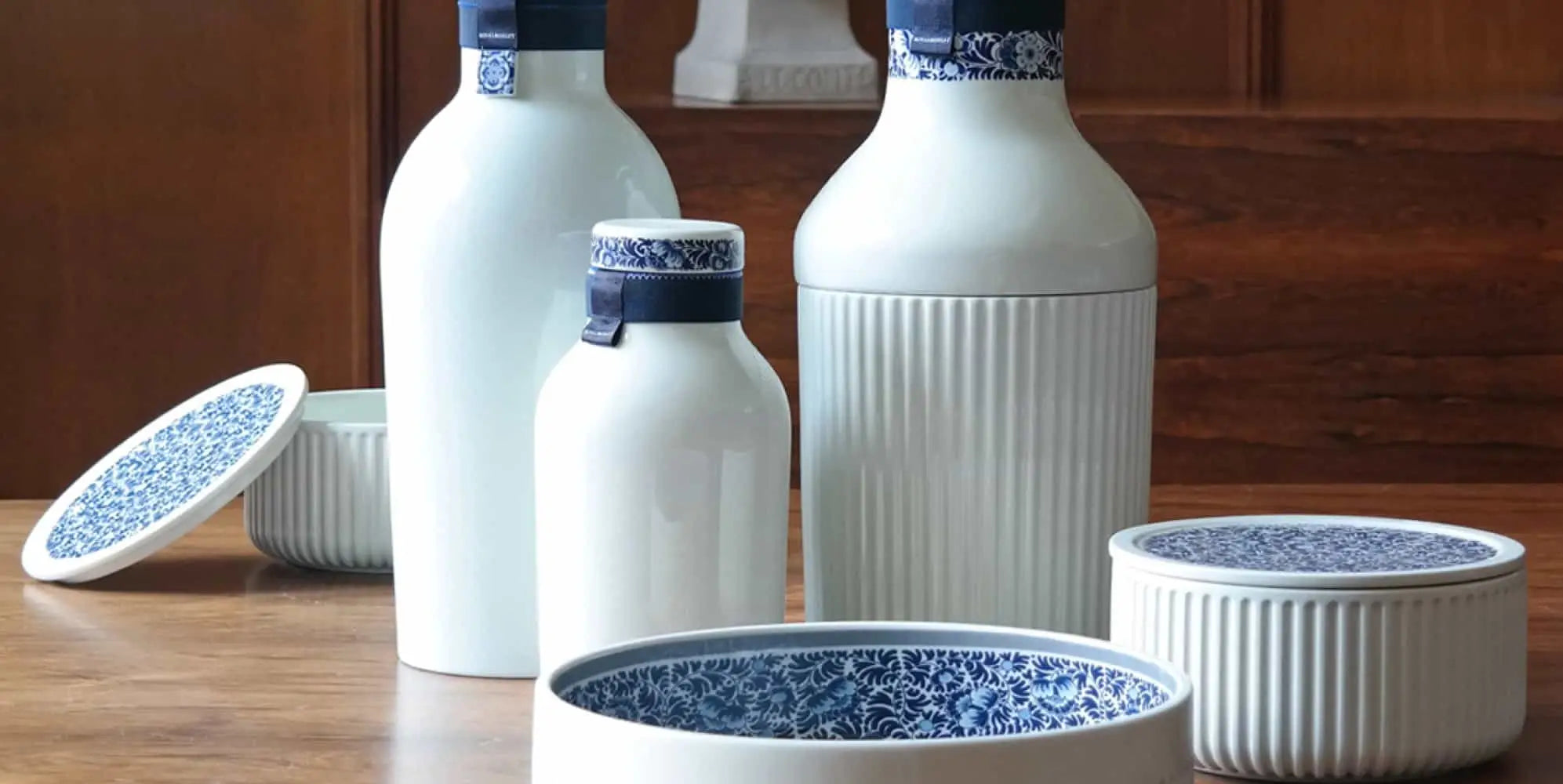 Witte keramische flessen en kommen met blauwe bloemenaccenten.